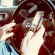 Woman using 2 cellphones whilst driving a car.