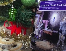 A Christmas Carol by Charles Dickens, alongside a christmas tree, tinsel and mince pies