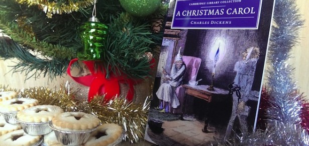 A Christmas Carol by Charles Dickens, alongside a christmas tree, tinsel and mince pies