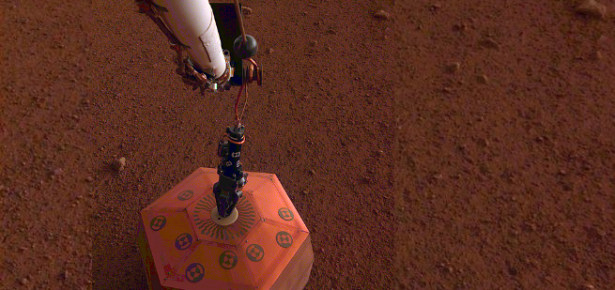 The robotic arm on NASA's InSight lander places a seismometer onto the surface of Mars.(credit: NASA/JPL-Caltech).
