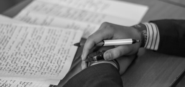 Hands holding a pen next to paper covered in writing